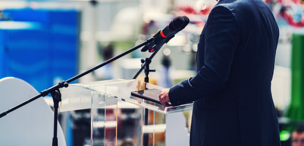 Male Speaker Standing In Front Of Microphones