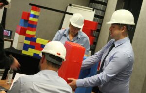 People wearing white helmets and stacking bricks