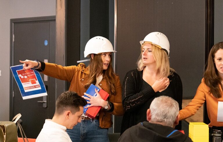 Person wearing white helmet talking and pointing