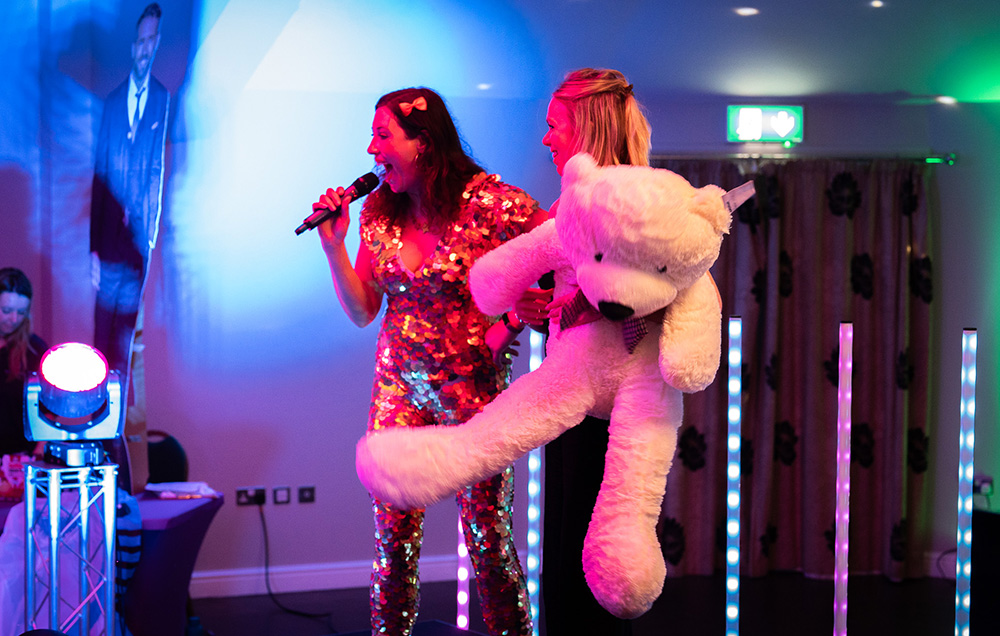 Host gifting woman on stage with a giant teddy bear