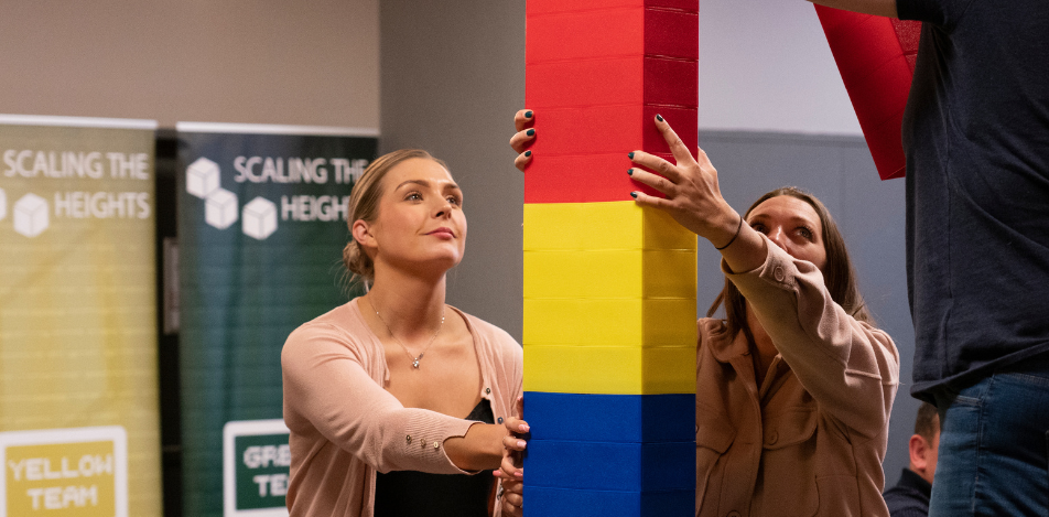 Scaling the heights 2 females building a tower with blue yellow red bricks