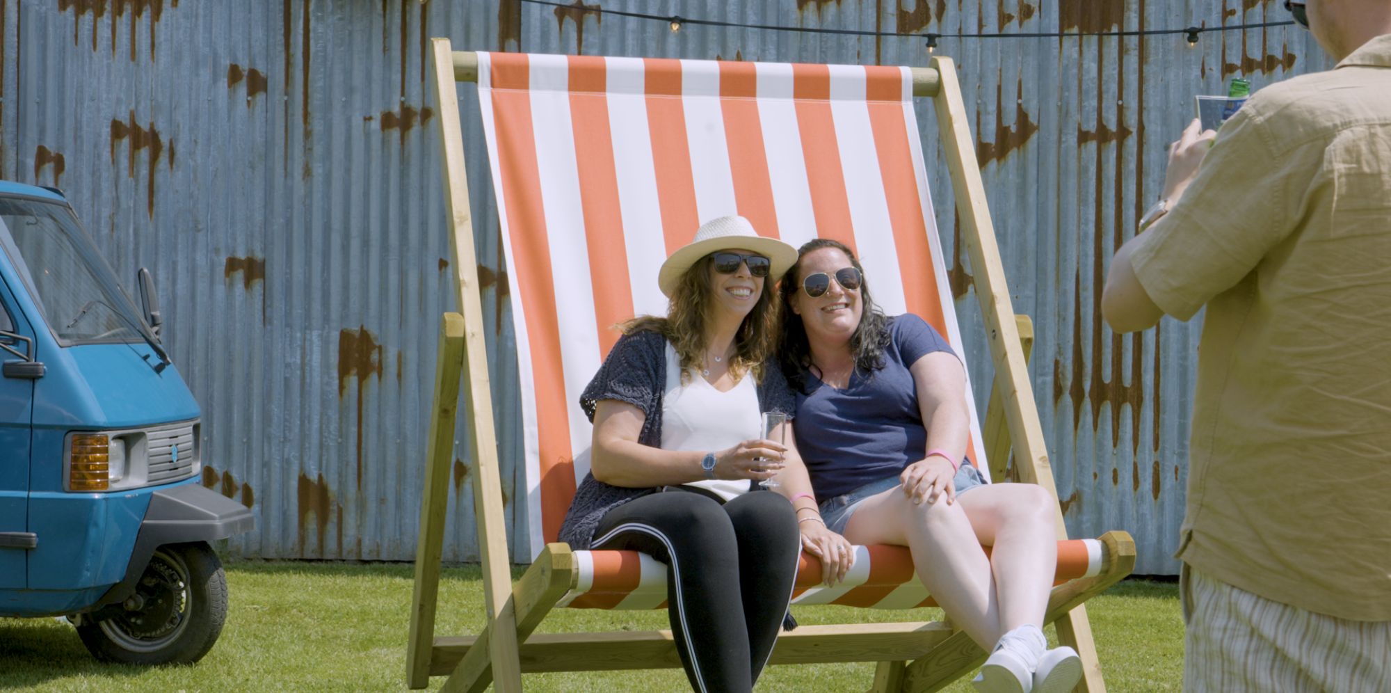 Friends having photo on giant deckchairs at festival